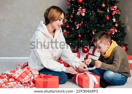 Woman with boy decorating christmas tree with gifts for new year