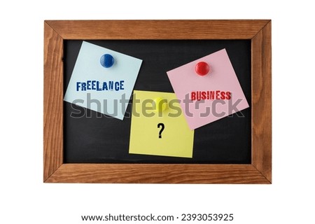 Words business and freelance work on colorful notepapers on magnetic blackboard isolated on white. Choosing between opportunities for own financial independence.