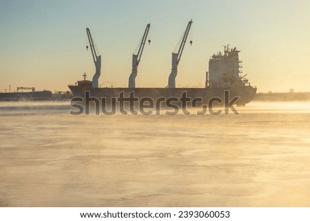  Cargo ship, ice classed bulk carrier in the ice and fog of a freezing river. High quality photo Royalty-Free Stock Photo #2393060053