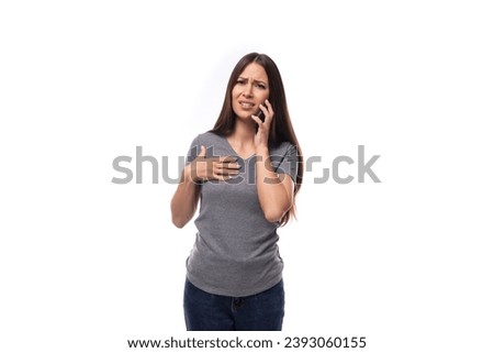 young caucasian brunette woman dressed in a casual gray t-shirt speaks on the phone on a white isolated background