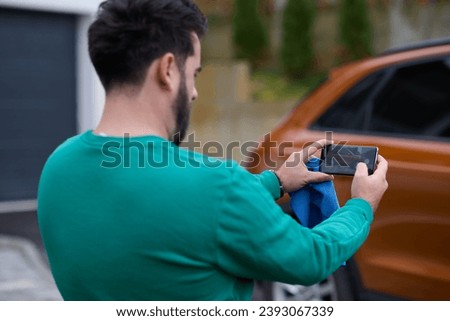 man taking photos on a smartphone of a car preparing for sale 