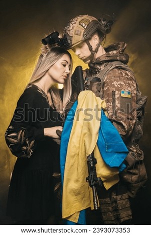 A couple in love at dawn during a battle in the smoke holds the flag of Ukraine in their hands. The concept of invincible love, the victory of Ukraine over the Russian invasion. 