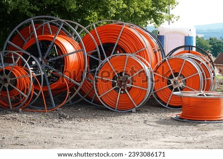 Various rolls of orange fiber optic cable for faster internet in rural areas. As underground cable for laying in the ground. Bad Munder Beber, Lower Saxony, Germany.                       Royalty-Free Stock Photo #2393086171