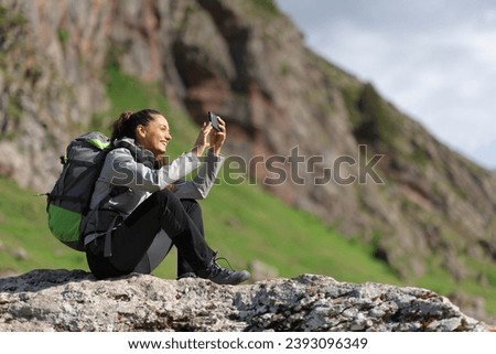 Hiker taking photos with smartphone sitting in nature