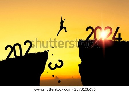 Welcome merry Christmas and happy new year in 2024,Silhouette Man jumping from 2023 cliff to 2024 cliff with yellow sky and sunlight in morning time.