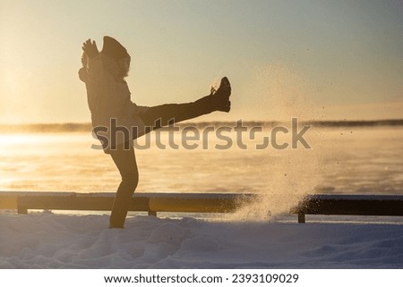 Happy girl kicking snow on beautiful winter day. High quality photo