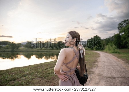 Young woman standing near lake during sunset,  beautiful nature.