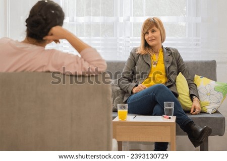 Two woman having a casual conversation sitting on a couch in the living room at home 
