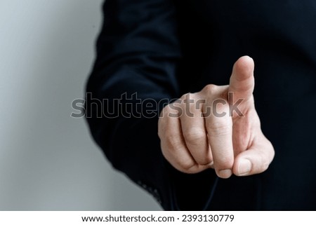 Pointing finger close-up shot of a man in a black business suit with copyspace and background