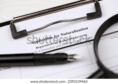N-400 Application for Naturalization blank form on A4 tablet lies on office table with pen and magnifying glass close up Royalty-Free Stock Photo #2393139465
