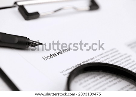 Model Release on A4 tablet lies on office table with pen and magnifying glass close up
