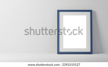 blue rectangular picture frame on white wall with blank paper mockup of diploma, certificate, photo or painting on neutral background