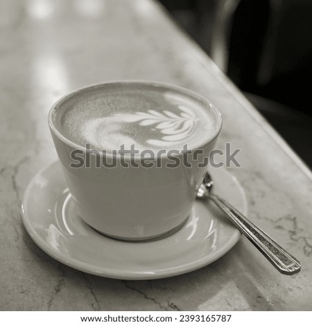 Black and white picture of a cup of latte macchiato in a cafe in the old town of Prague                               
