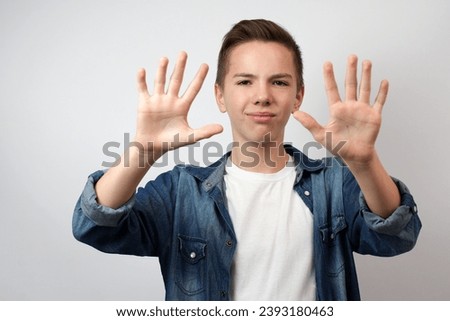 Serious teenage boy making stop gesture with hands, isolated on white background. No, thanks rejection