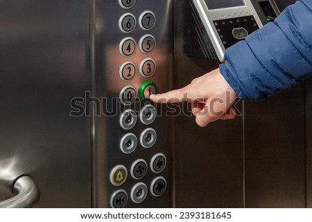 A man presses the floor button in the elevator of the business center.