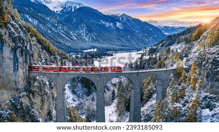 Aerial view of Train passing through famous mountain in Filisur, Switzerland. Landwasser Viaduct world heritage with train express in Swiss Alps snow winter scenery.  Royalty-Free Stock Photo #2393185093