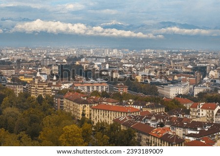 Panorama of the city Of Turin from the Mole Antonelliana on the background of the Alps and the clouds. Autumn city landscape, top view of rooftops and Royal Gardens.