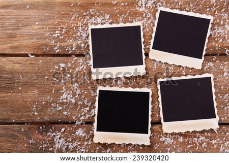 Blank photo frames and snowflakes on wooden table background