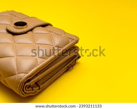 Women's wallet made of synthetic leather, khaki color, diamond pattern isolated on yellow.