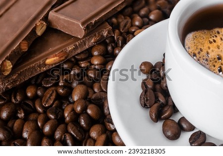 Chocolate, coffee beans and a cup of coffee on a saucer. Focus on coffee beans