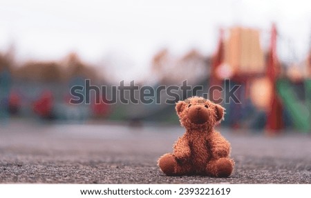 Lost teddy bear toy lying on playground floor in gloomy day,Lonely and sad brown bear doll lied down alone in the park, Lost toy or Loneliness concept,International missing Children day Royalty-Free Stock Photo #2393221619