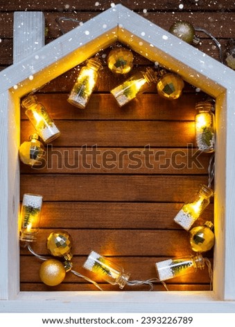 Tiny frame house on wooden background with Christmas decor layout and copy space. Gift for New Year, Christmas. Building, project, moving to new house, mortgage, rent and purchase real estate