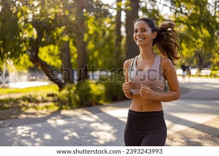 Attractive beautiful woman wearing sportswear running outdoors. Fit woman jogging outdoor. Workout exercise in the morning. Healthy and active lifestyle concept.