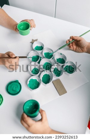A child draws a Christmas tree. Ideas for drawing with bright colors. Drawing children on a white background. A little girl draws with paint and brushes. The concept of children's development.