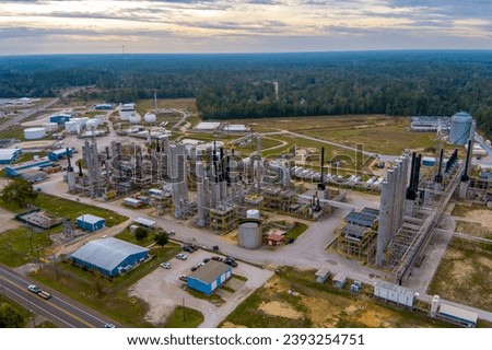 Aerial view of a Hydrocarbon or  Oil Refinery in  rural southeastern Texas with a dense forest in the background and a partly cloudy sky at sunrise. Royalty-Free Stock Photo #2393254751