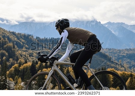 Male cyclist riding gravel bike on gravel road in autumn mountains. Cyclist practicing on gravel road. Gravel biking during the autumn. Sport motivation. Adventure travel on bike. Mountain background.