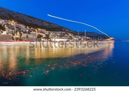 Long Exposure photography of a naval lights white and red reflected in the sea, bay water. Night, Dubrovnik coastline in the background