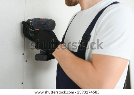 Worker builder installs plasterboard drywall at a construction. Royalty-Free Stock Photo #2393274585