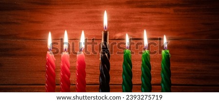 Happy Kwanzaa. African American holiday. Seven burning candles, red, black and green, in kinara candlestick. Symbols of African heritage. Banner format