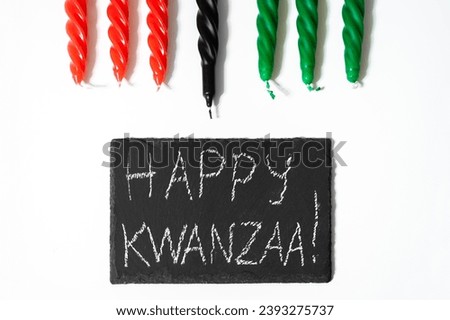 Happy Kwanzaa concept. African-American holiday. Congratulatory lettering and seven candles - red, black and green. African heritage symbol on a white background.