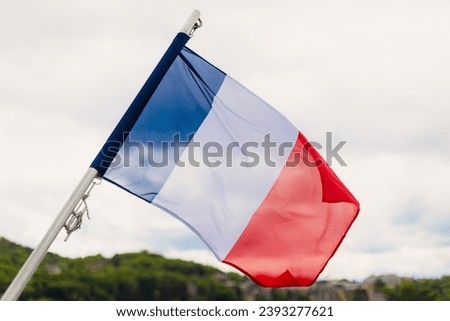 France's flag on a boat pole, in the end, waving in the wind. Lake in the background