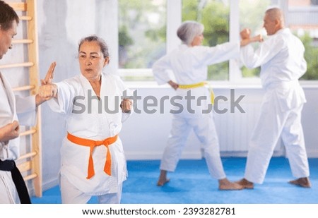 Senior karate practitioner engage in fierce fight, perseverance during martial arts discipline, middle-aged teacher and mature followers. Work on yourself, increase endurance, determination, courage Royalty-Free Stock Photo #2393282781