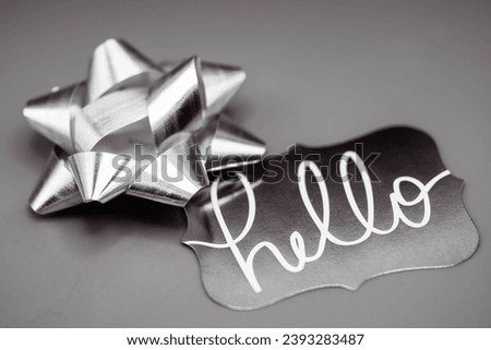 Silver gray hello song with same color matching bow perfect for copy space or vector icon for small business card or sign for store front