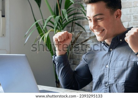 Man sit at desk read e-mail on laptop makes yes gesture feels happy. Male entrepreneur get great business news, celebrate career growth, advance. Achievement, win, moment of auction victory concept Royalty-Free Stock Photo #2393295133