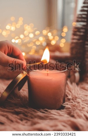 A match lights a candle close-up, Christmas mood in pink colors.