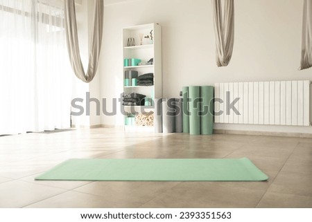 Gym interior with green yoga mat, big windows, no people. Copy space.  Royalty-Free Stock Photo #2393351563