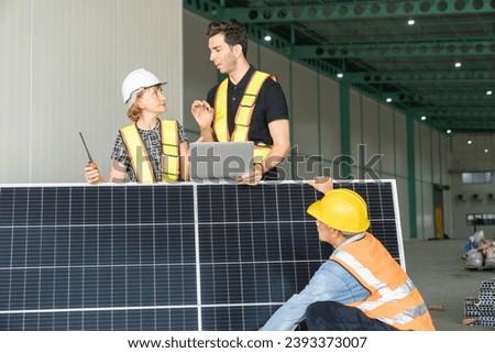 Team of engineers and technicians working together on solar panels in a warehouse.