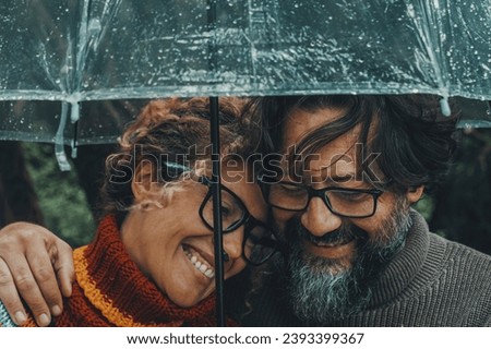 Romantic couple in love under umbrella in rainy day. Man and woman enjoy relationship and happiness together in winter autumn rain. Romance and people smiling end hugging at the park in leisure moment Royalty-Free Stock Photo #2393399367