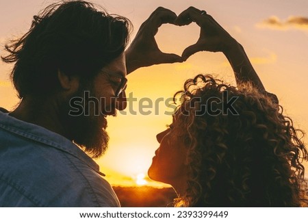 Peace and love with couple doing heart gesture sign with both hands together. Sunset light and outdoor romantic activity with adult man and woman enjoying relationship. Stop war concept