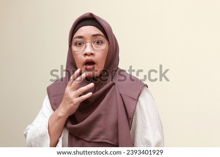 An Asian Muslim woman with surprise expression.
