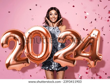 Portrait of a cheerful beautiful girl wearing sparkle dress standing under confetti rain and celebrating isolated over pink background. New year 2024