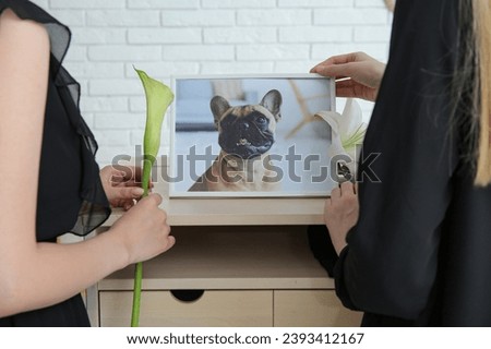 Women with picture of dog and flowers in room, closeup. Pet funeral