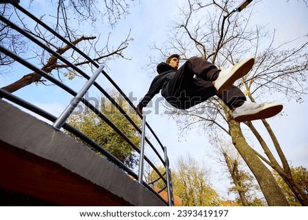 Free runner, young guy jumps over parking lot, practice Parkour in public park among over sky view. Eye fish filter. Concept of lifestyle, extreme kinds of sport, freestyle, activity, motion. Ad