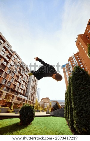 Fish eye effect photo of young man, guy performing insane tricks and breathtaking flips in air in motion. Extreme sport activity, free running. Concept of lifestyle, freestyle, activity, motion. Ad