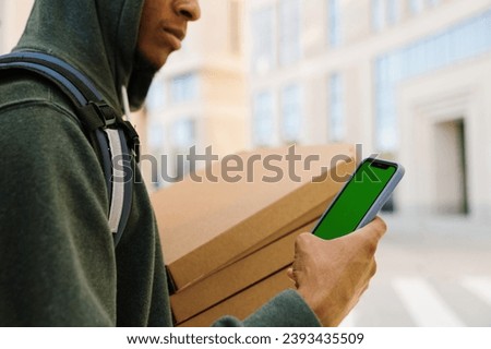 A pizza deliveryman with a mobile phone with a green screen. A place for your advertising.