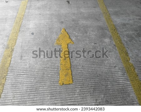 The directional arrows in the public transportation parking area in yellow color with a rough textured floor